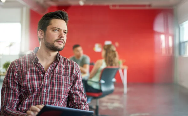 Diseñador masculino confiable trabajando en una tableta digital en el espacio de oficina creativo rojo — Foto de Stock