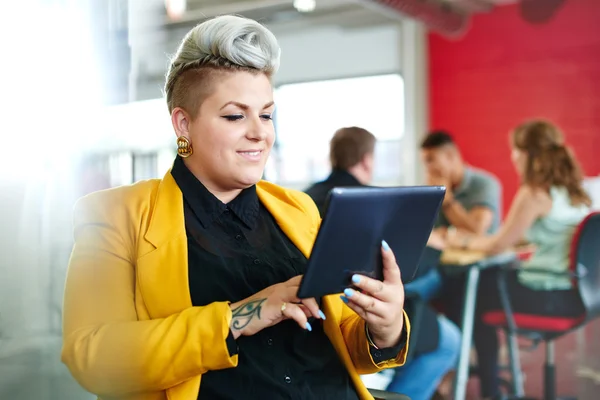 Designer feminina confiante e nervosa trabalhando em um tablet digital no espaço de escritório criativo vermelho — Fotografia de Stock