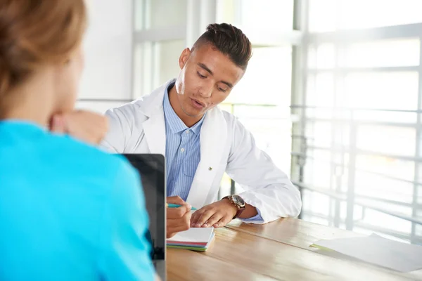 Team van arts en verpleegkundige bespreken een patiënt diagnose zitten aan de balie in heldere moderne kantoor — Stockfoto