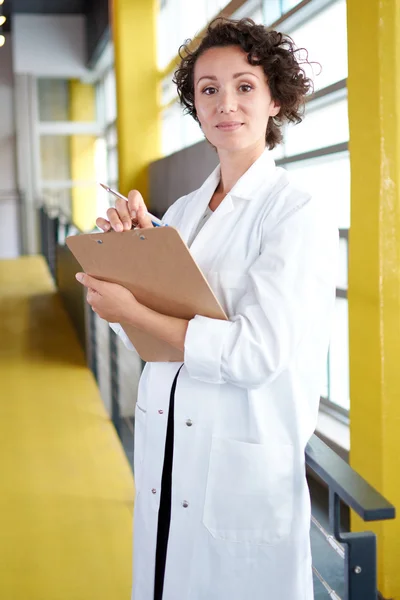 Retrato de uma médica feminina segurando seu prontuário no hospital moderno brilhante — Fotografia de Stock