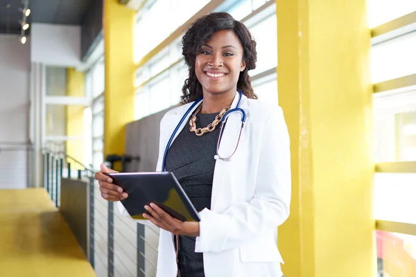 Porträt einer Ärztin mit ihrer Patientenakte auf einem digitalen Tablet in einem hellen modernen Krankenhaus — Stockfoto