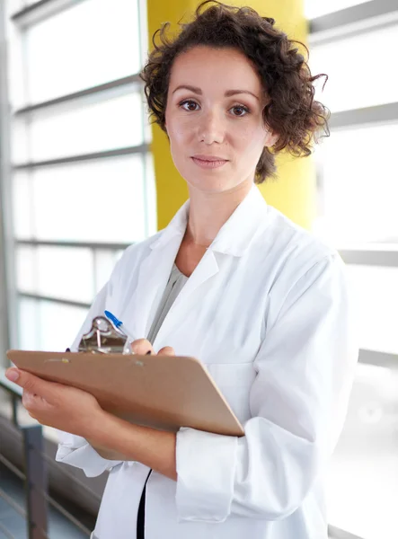 Portrait d'une femme médecin tenant son dossier patient dans un hôpital moderne lumineux — Photo