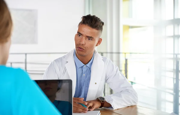 Team van arts en verpleegkundige bespreken een patiënt diagnose zitten aan de balie in heldere moderne kantoor — Stockfoto