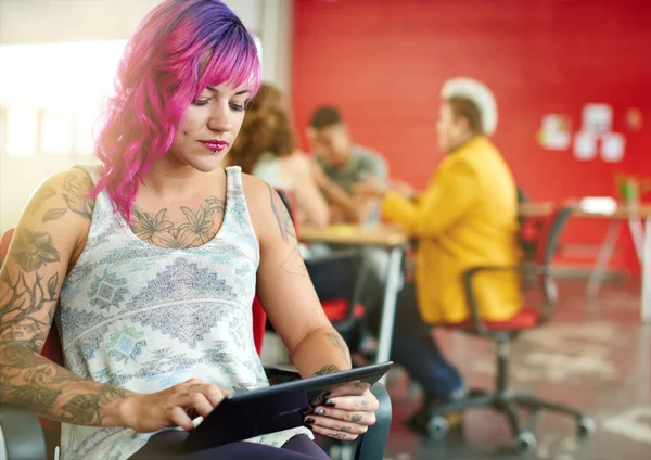 Designer féminin confiant et énergique travaillant sur une tablette numérique dans un espace de bureau créatif rouge — Photo