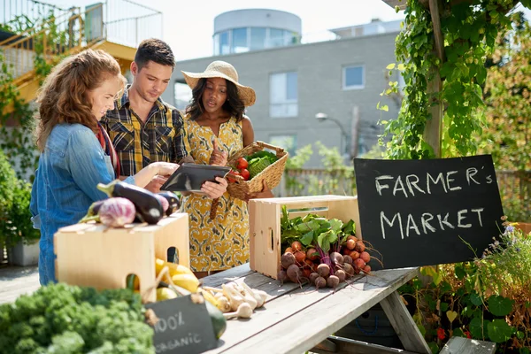 Mujer amable que atiende un puesto de verduras orgánicas en un mercado de agricultores y la venta de verduras frescas del jardín de la azotea —  Fotos de Stock