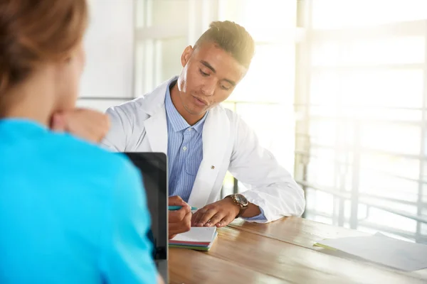 Team van arts en verpleegkundige bespreken een patiënt diagnose zitten aan de balie in heldere moderne kantoor — Stockfoto