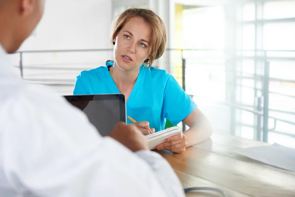 Team van arts en verpleegkundige bespreken een patiënt diagnose zitten aan de balie in heldere moderne kantoor — Stockfoto