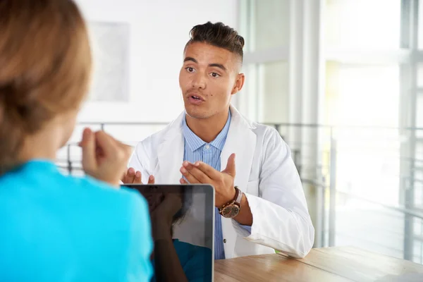 Team van arts en verpleegkundige bespreken een patiënt diagnose zitten aan de balie in heldere moderne kantoor — Stockfoto