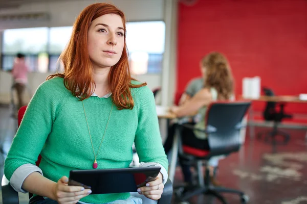 Fiduciosa designer donna che lavora su un tablet digitale in uno spazio ufficio creativo rosso — Foto Stock