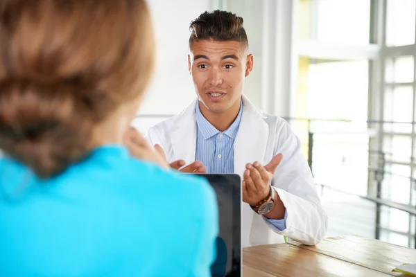 Team van arts en verpleegkundige bespreken een patiënt diagnose zitten aan de balie in heldere moderne kantoor — Stockfoto