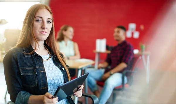 Diseñadora femenina segura trabajando en una tableta digital en un espacio de oficina rojo creativo — Foto de Stock