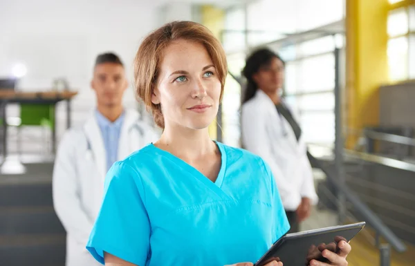 Portrait of a friendly caucasian female doctor and team in bright modern office — Stok Foto