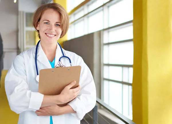 Retrato de una doctora sosteniendo su historia clínica en un hospital moderno y luminoso — Foto de Stock