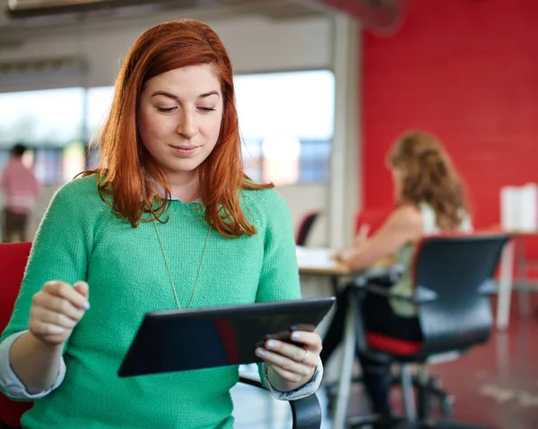 Fiduciosa designer donna che lavora su un tablet digitale in uno spazio ufficio creativo rosso — Foto Stock