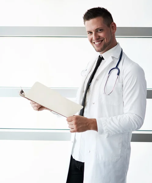 Parlak modern hastanede hasta çizelgesini tutan bir erkek doktor portresi — Stok fotoğraf