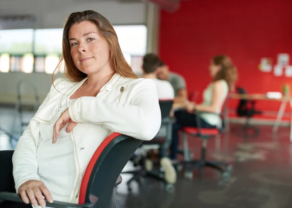 Diseñadora femenina segura trabajando en una tableta digital en un espacio de oficina rojo creativo —  Fotos de Stock