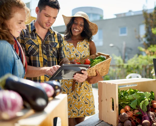 Friendly woman tending an organic vegetable stall at a farmers market and selling fresh vegetables from the rooftop garden — Stock Photo, Image