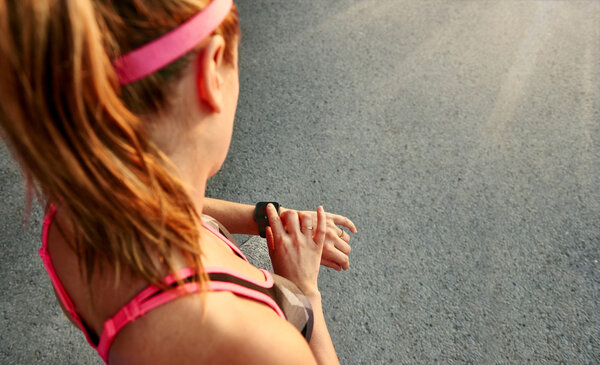 Женщина программирует свои умные часы перед пробежкой, чтобы отслеживать производительность
