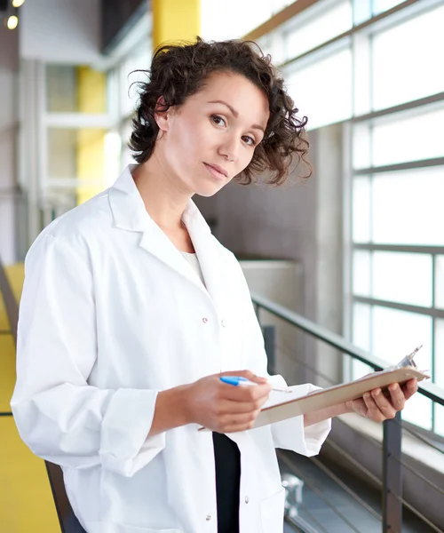 Portrait of a female doctor holding his patient chart in bright modern hospital — Stok Foto