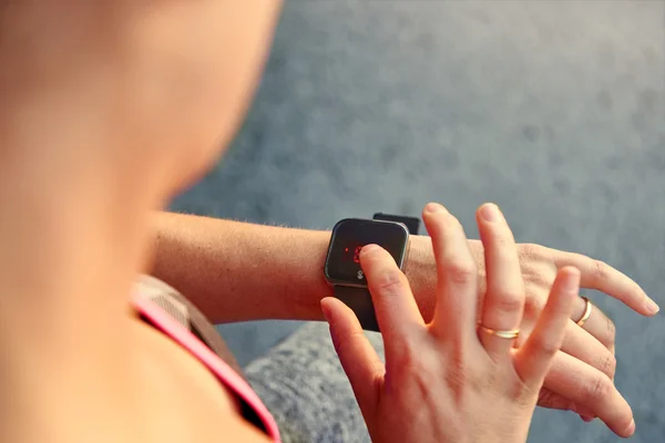 Женщина программирует свои умные часы перед пробежкой, чтобы отслеживать производительность — стоковое фото