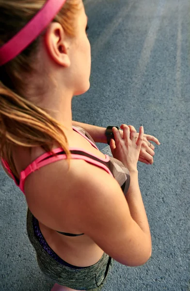 Vrouw haar smartwatch programmeersyntaxis gaan joggen voor het bijhouden van prestaties — Stockfoto