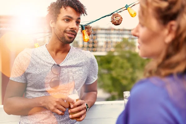 Multietnické millenial pár flirtování zároveň s drinkem na střeše terrasse při západu slunce — Stock fotografie