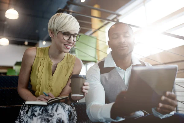 Two creative millenial small business owners working on social media strategy using a digital tablet while sitting in staircase — Stock Photo, Image