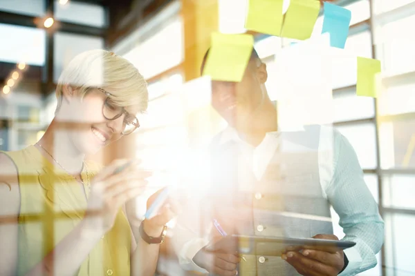 Zwei kreative Kleinunternehmer aus der Jahrtausendwende, die an einem Social-Media-Brainstorming mithilfe von Klebezetteln in Fenstern arbeiten — Stockfoto