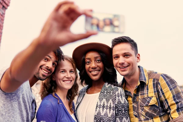 Grupo multiétnico milenario de amigos tomando una foto selfie con teléfono móvil en la terraza de la azotea al atardecer — Foto de Stock