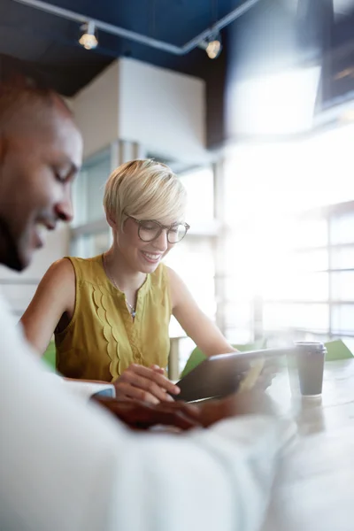 Two creative millenial small business owners working on social media strategy using a digital tablet while sitting at desk — Stock Photo, Image