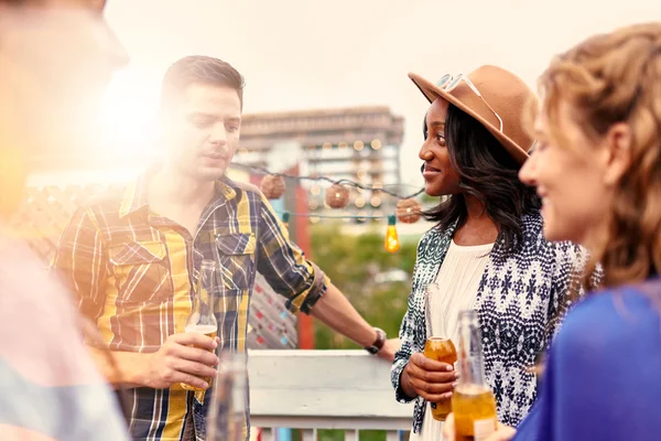 Multi-ethnic millenial group of friends partying and enjoying a beer on rooftop terrasse at sunset — Stock Photo, Image