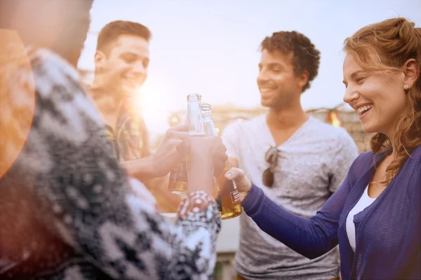 Grupo multi-étnico milenar de amigos festejando e desfrutando de uma cerveja no terraço do último piso ao pôr do sol — Fotografia de Stock