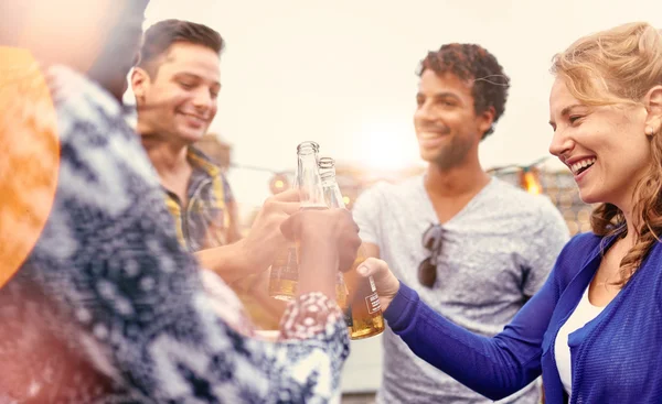 Grupo multi-étnico milenar de amigos festejando e desfrutando de uma cerveja no terraço do último piso ao pôr do sol — Fotografia de Stock