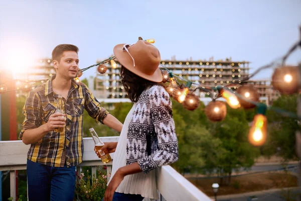 Multi-etnico millenial coppia flirtare mentre si beve un drink sul terrazzo sul tetto al tramonto — Foto Stock