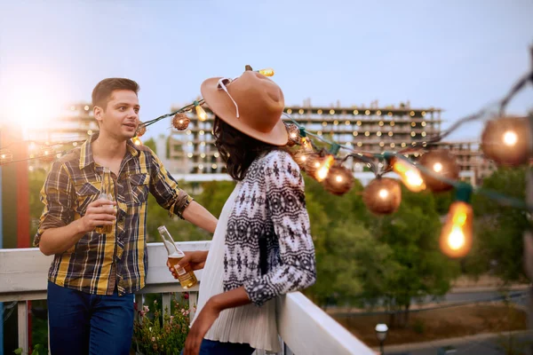 Casal milenar multi-étnico flertando enquanto toma uma bebida no terraço do telhado ao pôr-do-sol — Fotografia de Stock