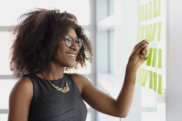 Portrait of a smiling business woman with an afro in bright glass office