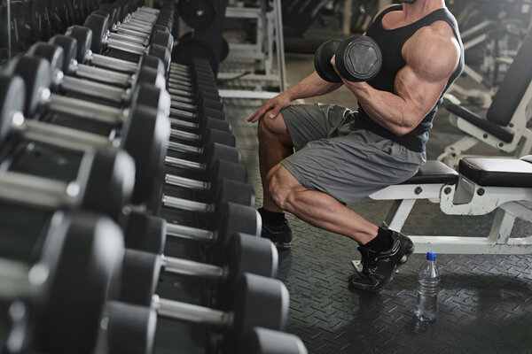 bodybuilder working out with bumbbells weights at the gym