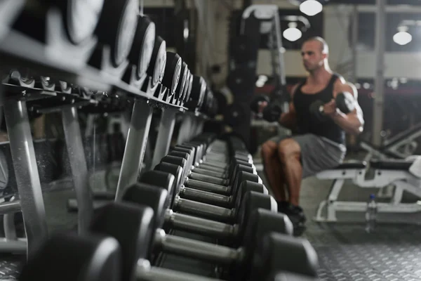 Bodybuilder träna med bumbbells vikter på gymmet — Stockfoto