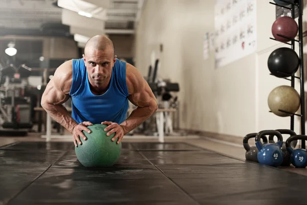 Bodybuilder working out and doing push upsat the gym while — Stock Photo, Image