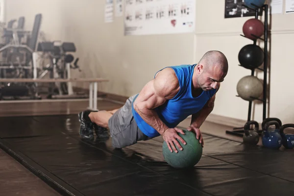 Bodybuilder working out and doing push upsat the gym while — Stock Photo, Image