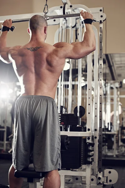 Bodybuilder uit te werken in de sportschool terwijl het gebruiken van fitnesstoestel — Stockfoto