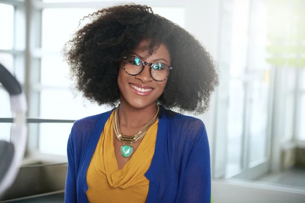 Porträt einer lächelnden Frau mit einem Afro am Computer im hellen Glasbüro — Stockfoto