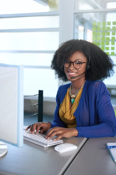 Portret van een lachende medewerker van de klantenservice met een afro op de computer gebruik van de hoofdtelefoon — Stockfoto