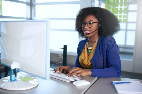 Retrato de un representante de servicio al cliente sonriente con un afro en el ordenador usando auriculares — Foto de Stock