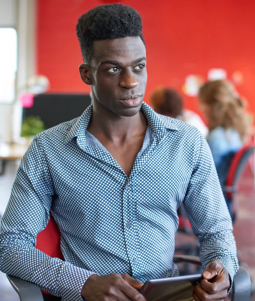 Diseñador masculino confiable trabajando en una tableta digital en el espacio de oficina creativo rojo —  Fotos de Stock