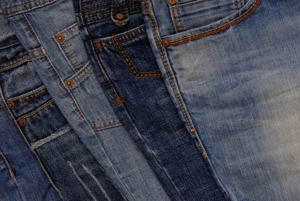 Blue denim background, pile of different jeans — Stock Photo, Image