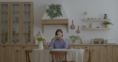 30 'lu yaşlardaki genç bir kadın mutfakta kahve içmekten hoşlanıyor. Evden çalışan bir kadın girişimci var. Konforlu ahşap mutfakta biri var.. 