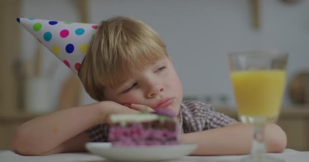 Portrait of pensive preschool birthday kid looking at piece of cake and sighing sadly. Child is unhappy because of no guests. Birthday boy alone at home. Close up. — Stock Video