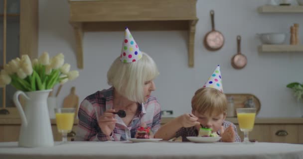 Vorschulkind mit Partyhut feiert Geburtstag zu Hause. Familie isst Geburtstagstorte. Geburtstagsfeier zu Hause. — Stockvideo