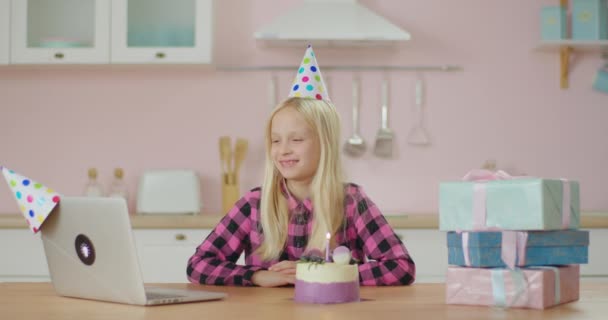 Κορίτσι γιορτάζει γενέθλια σε απευθείας σύνδεση κάθεται μόνη στο σπίτι. Η εορτάζουσα κάνει μια ευχή και φυσάει το φως των κεριών μιλώντας στο λάπτοπ. Online εορτασμός γενεθλίων. — Αρχείο Βίντεο